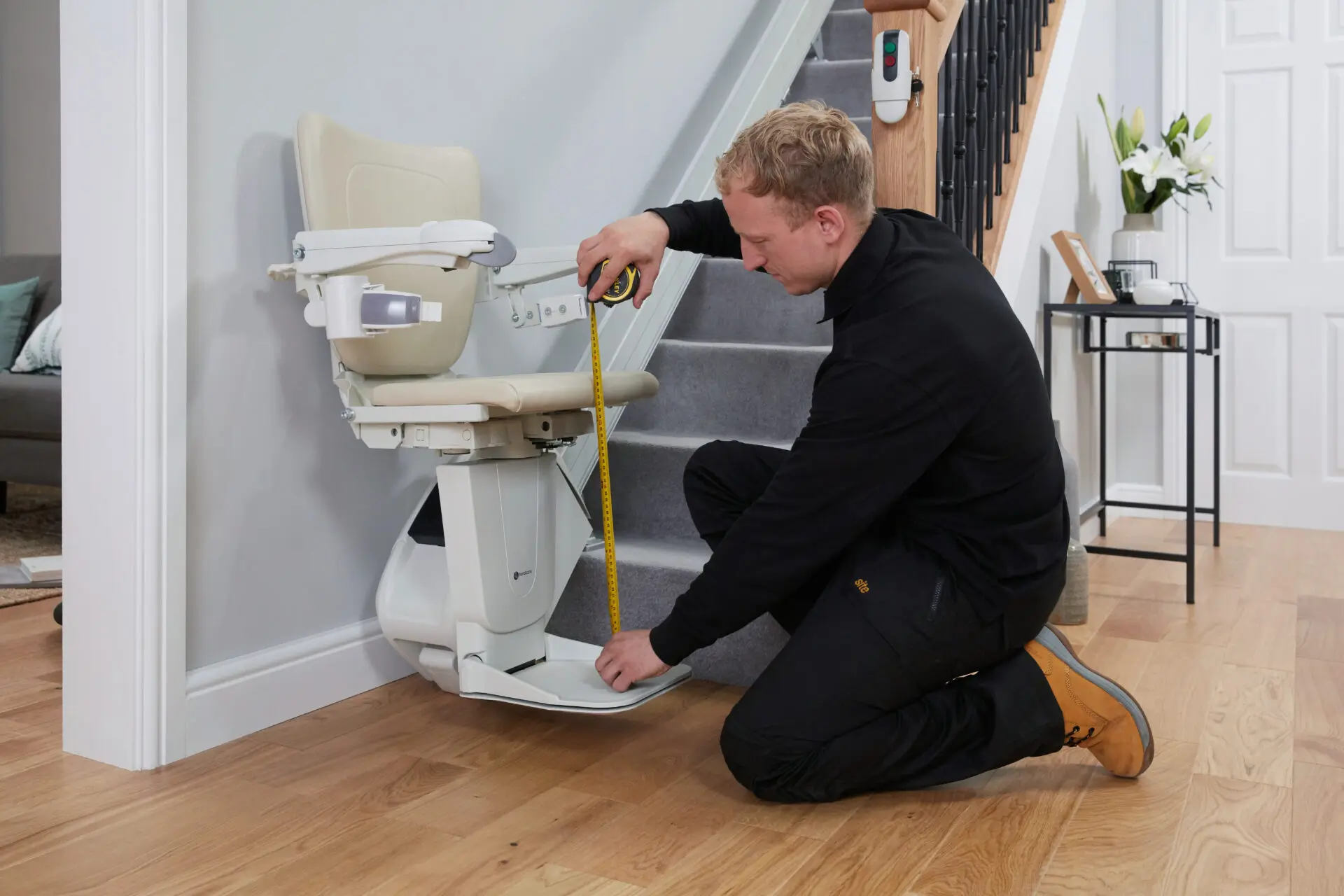 Engineer uses tape measure to check the height of the seat on a newly-installed Handicare 1100.