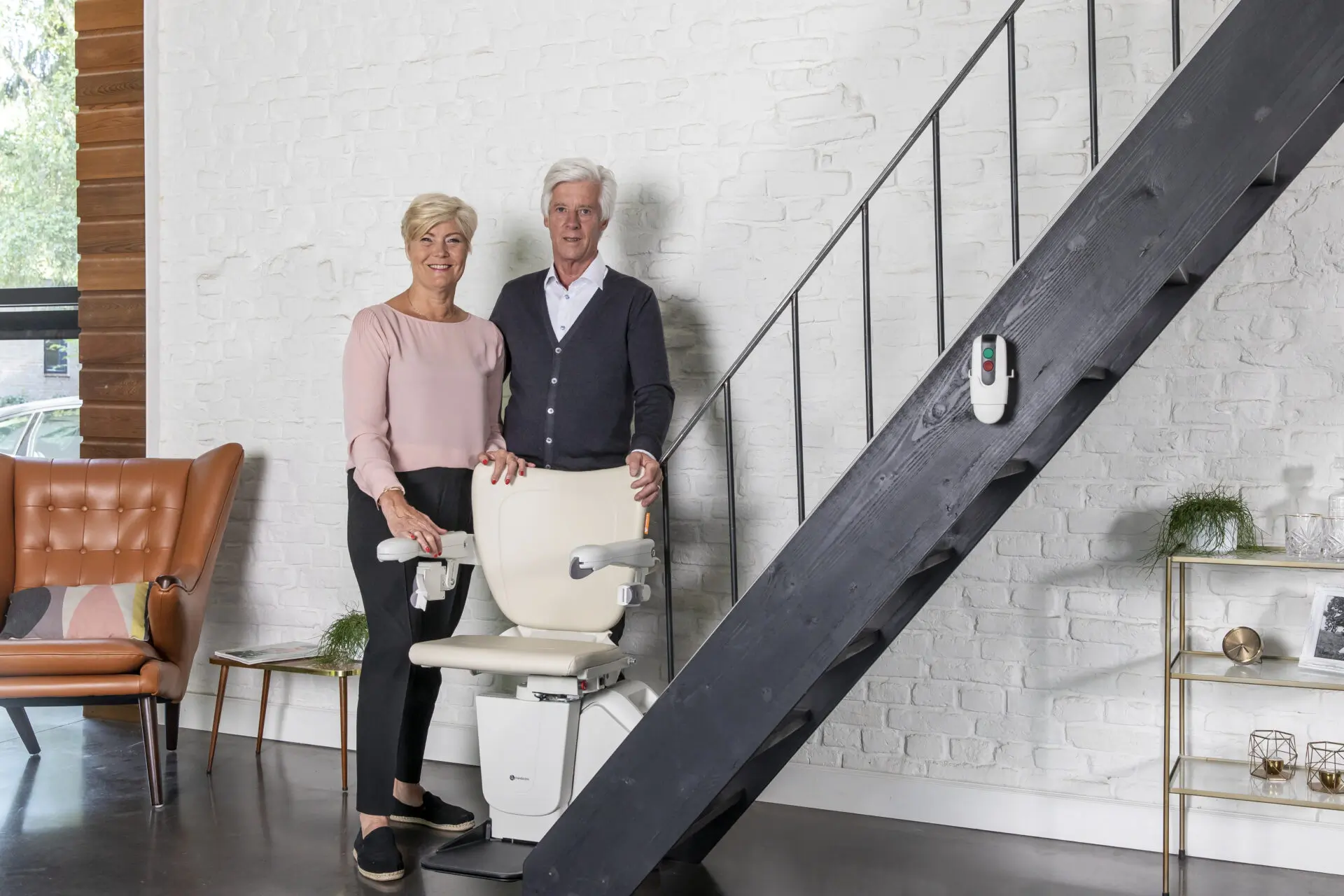 An elderly couple in a modern apartment use their 1100 Handicare stairlift.