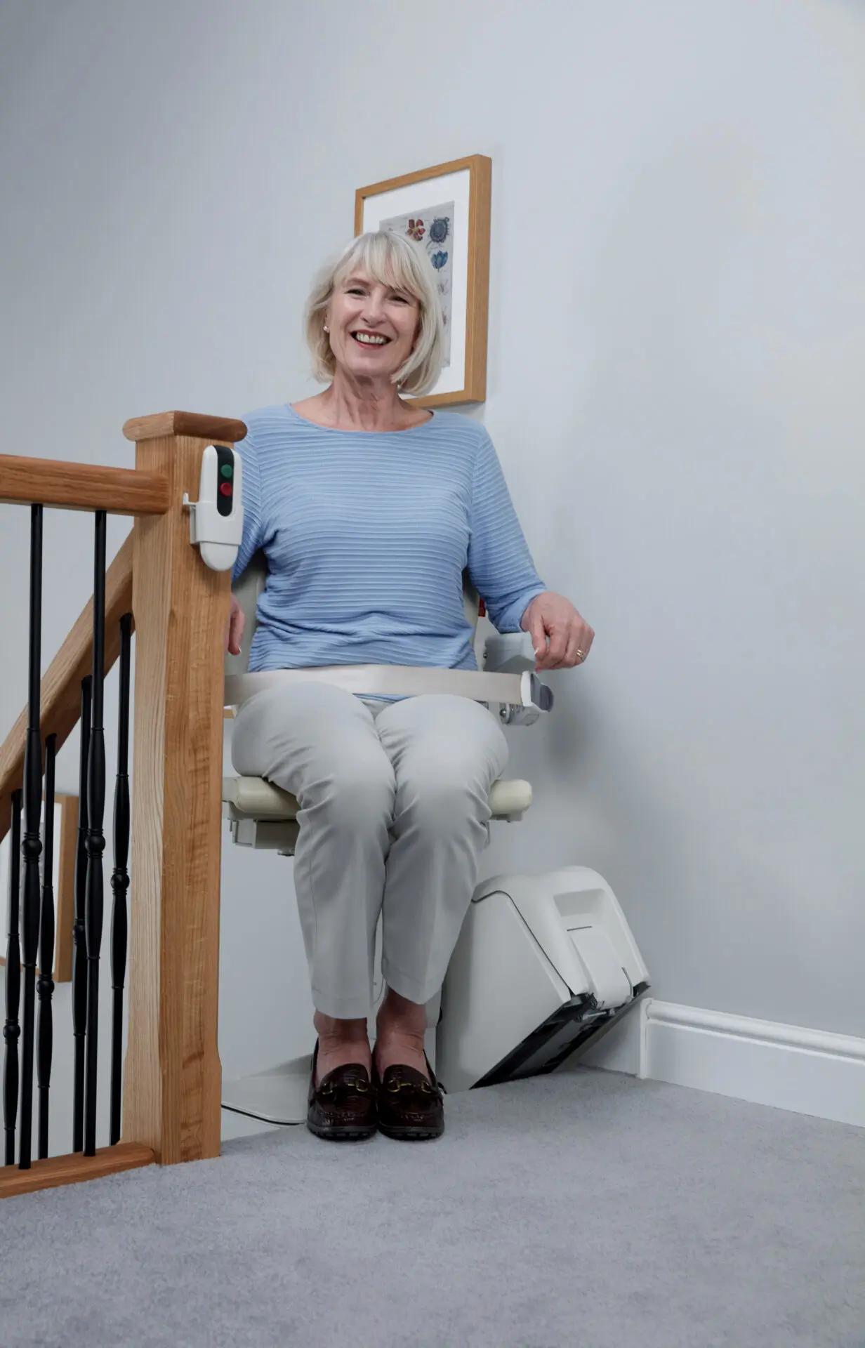 A woman uses her Handicare 1100 stairlift to reach the top of the stairs.