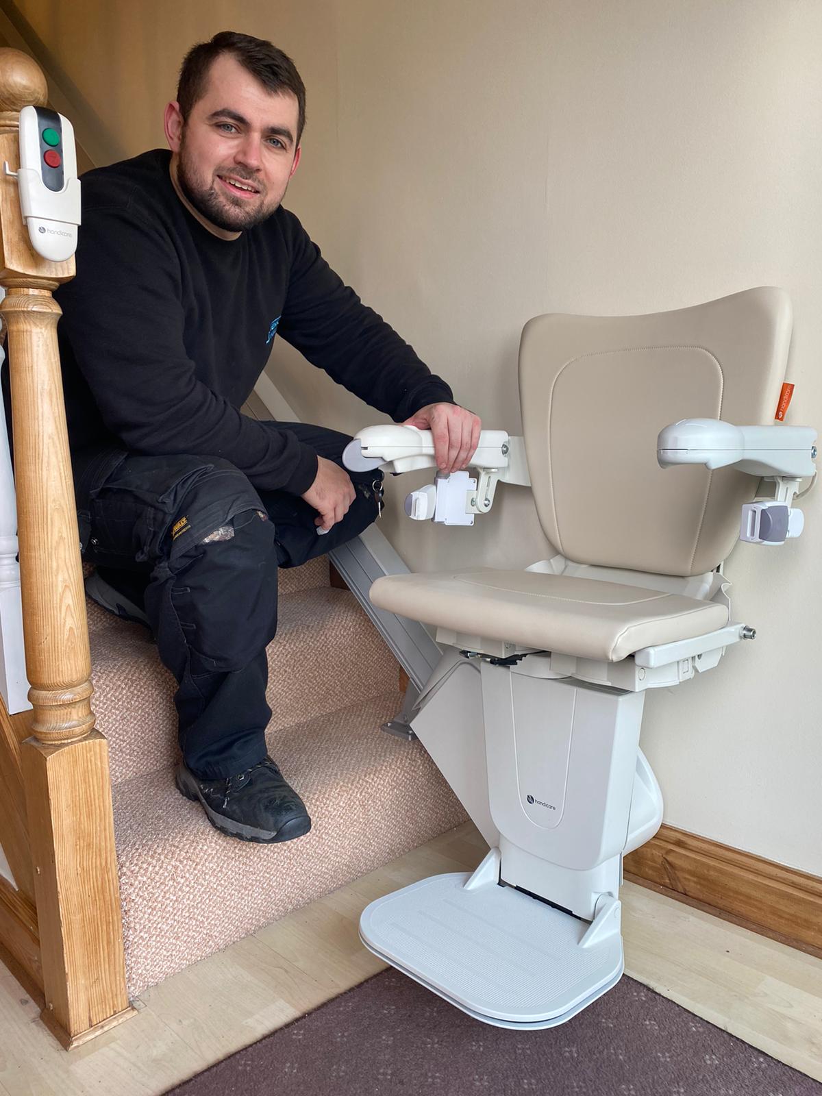 An engineer smiles beside a newly repaired straight stairlift.