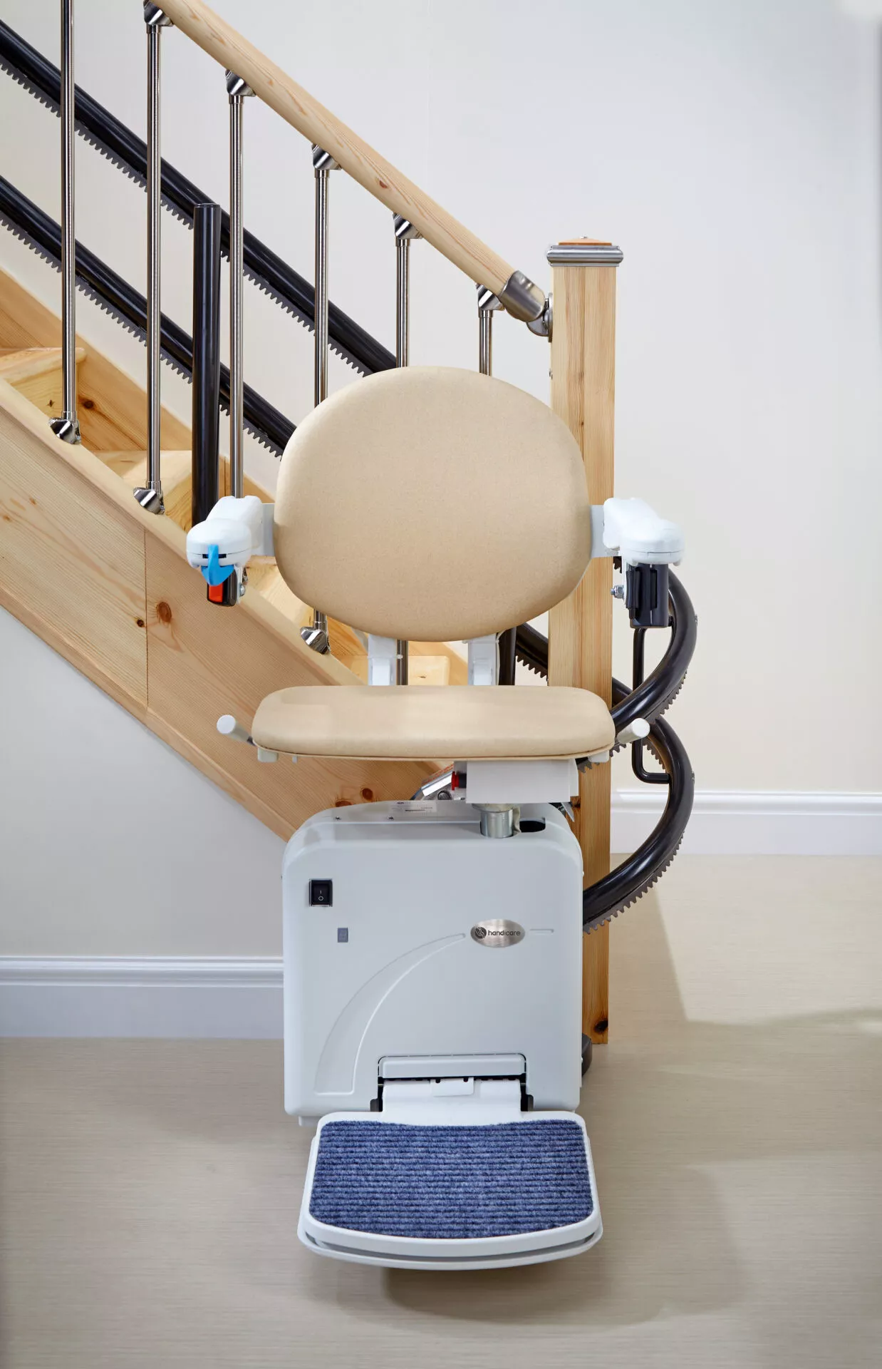 Rental Stairlift with beige upholstery and a blue, carpeted footrest that is folded out.