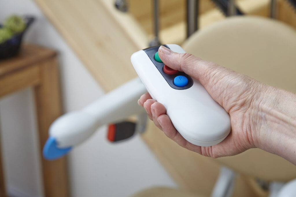 senior using the handicare 2000 remote to control the stair lift