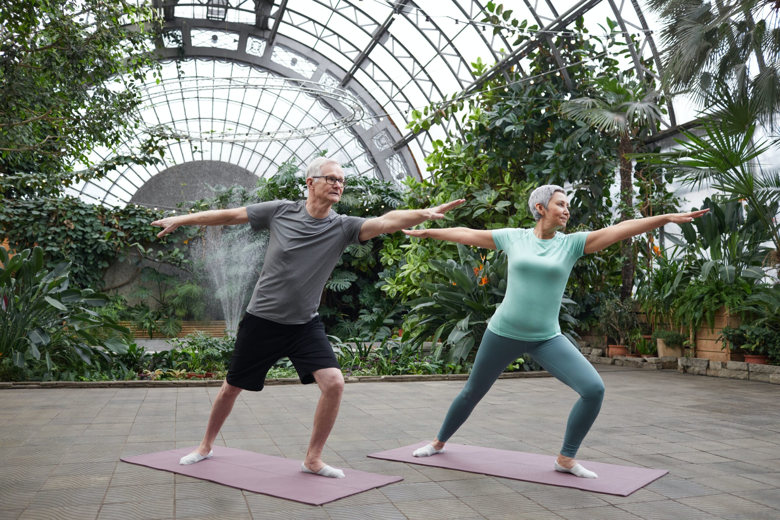 Senior Couple performing yoga in nature enclosure