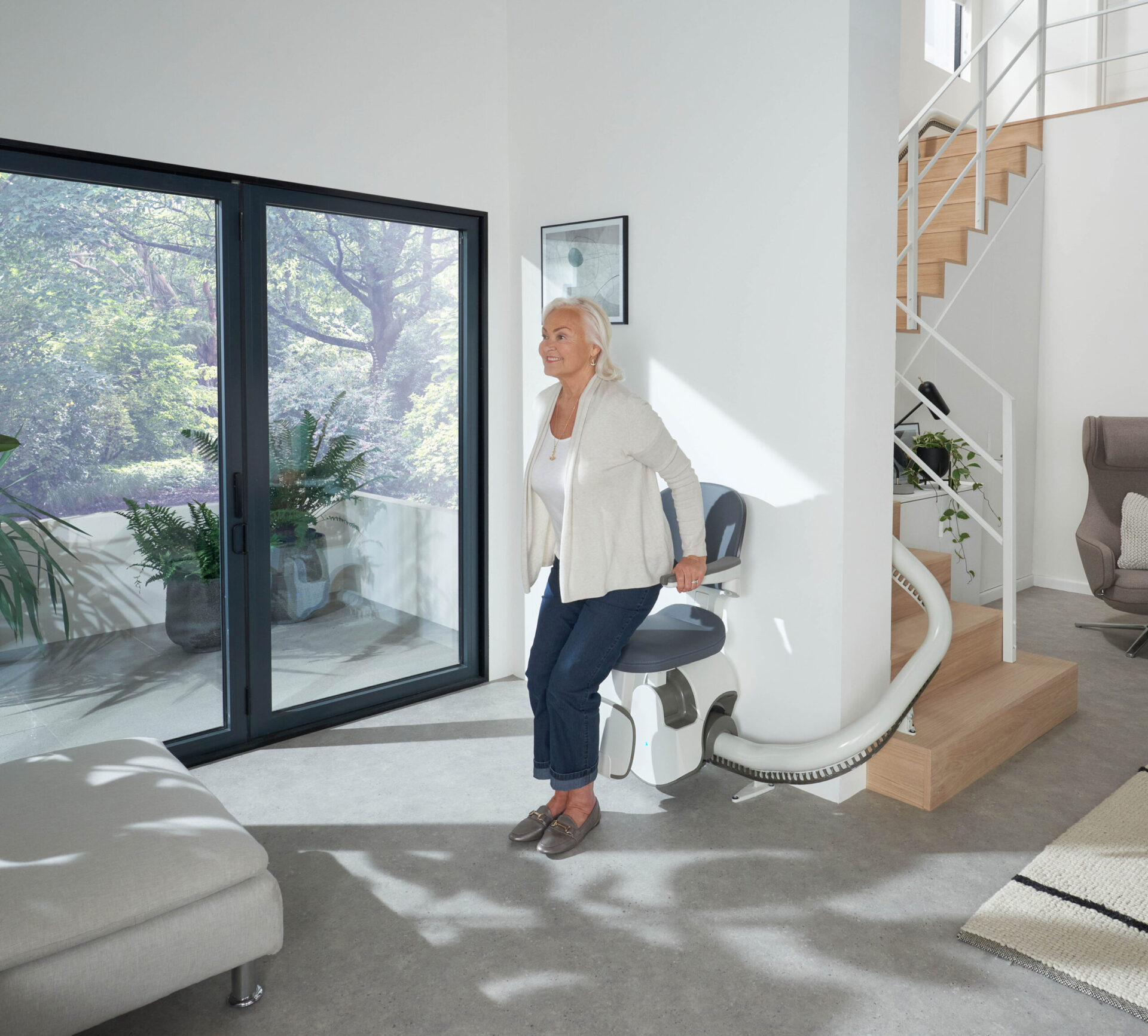 an elderly lady sitting down onto the Flow X stairlift