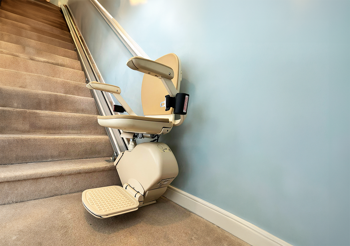 A brooks 130 straight stairlift parked comfortably at the bottom of a carpeted staircase