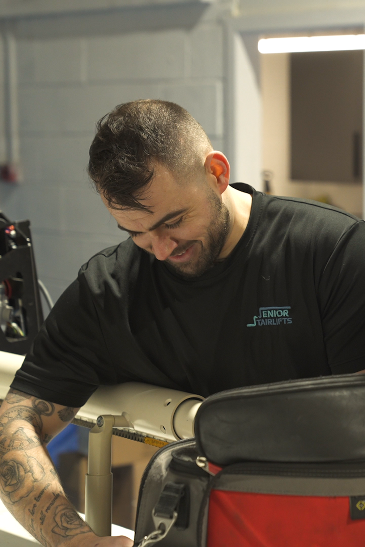 A stairlift engineer happily repairing a stairlift rail