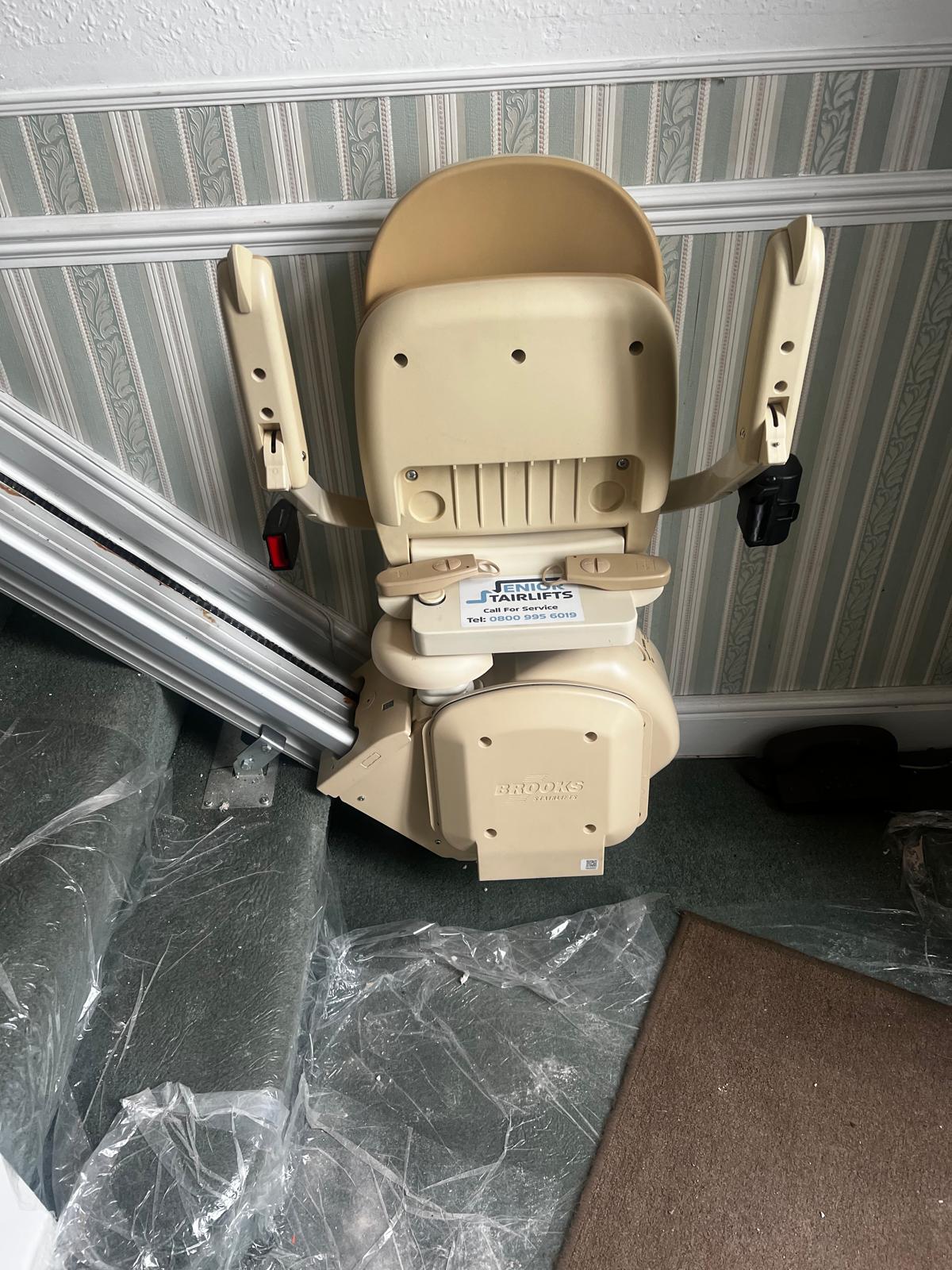 A Brooks 130 Stairlift parked at the bottom of the stairs. This one was neatly installed by Senior Stairlifts.