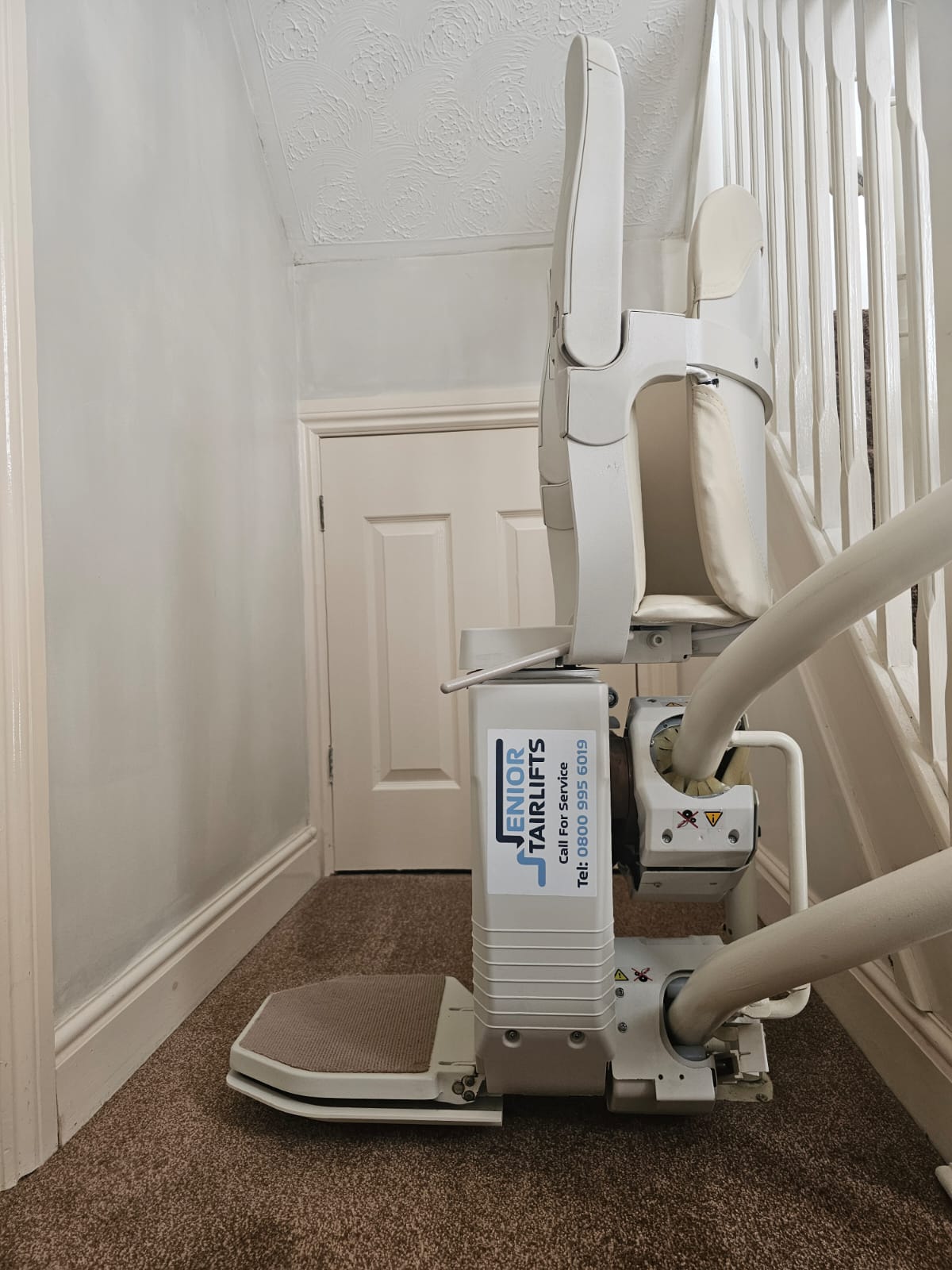 A side view of a stannah 260 stairlift with a Senior Stairlifts service sticker on the side