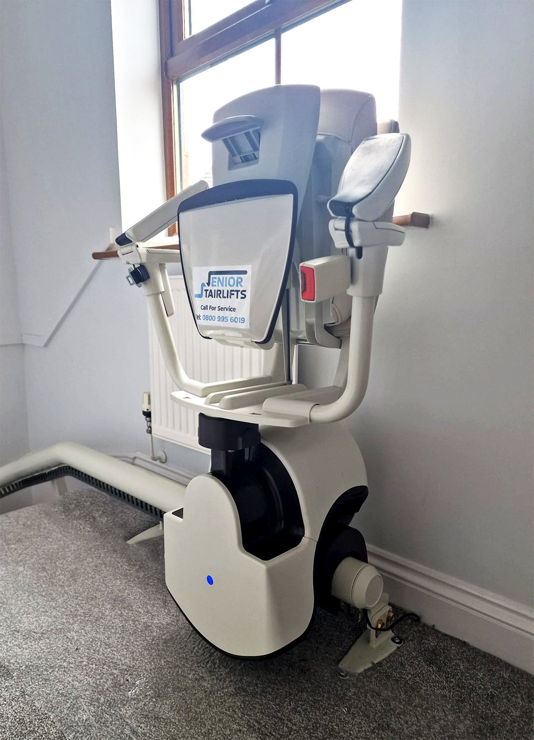 A Thyssenkrupp Flow stairlift resting at the top of a staircase