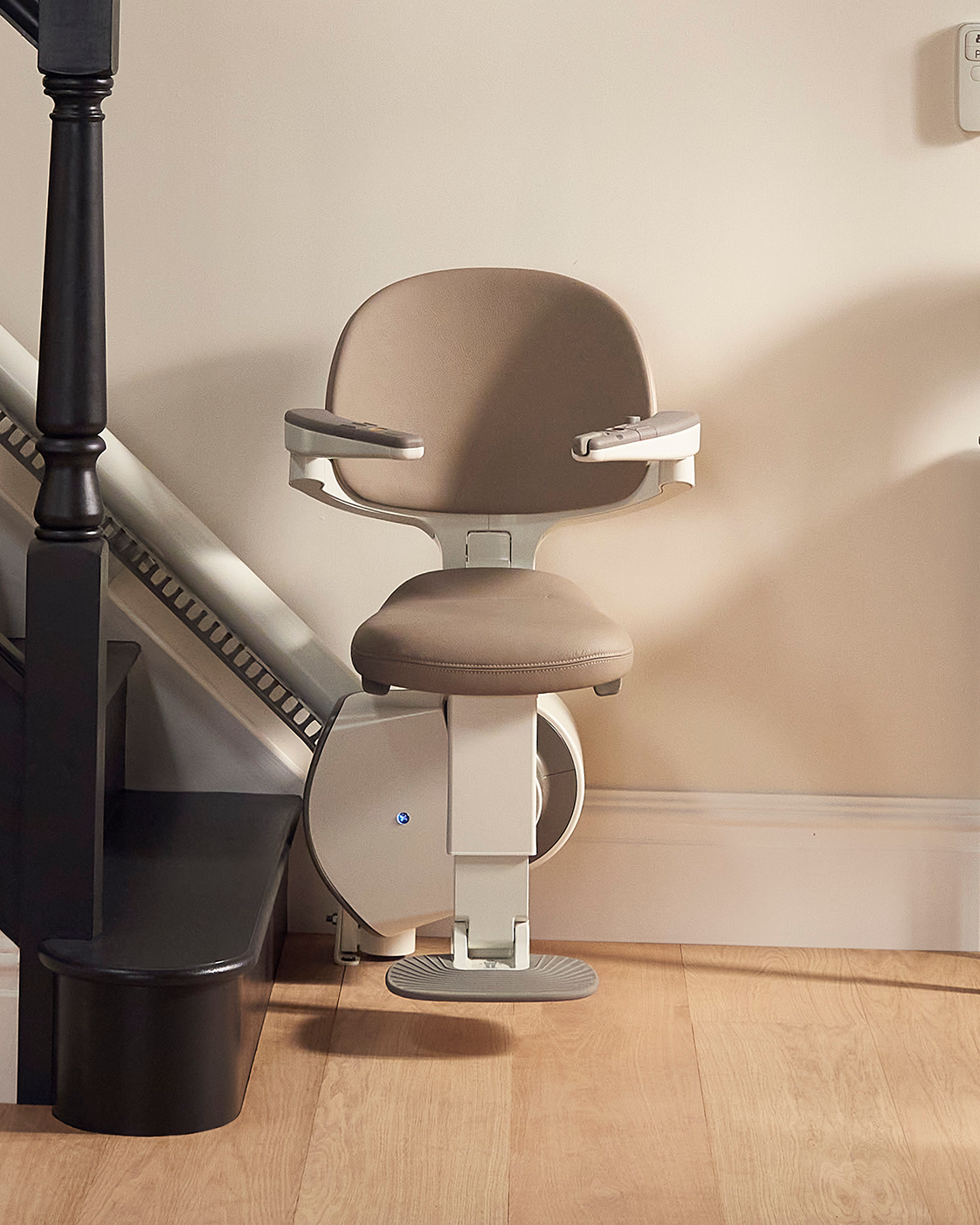 A Flow X curved Stairlift with cream brown leather upholstery.