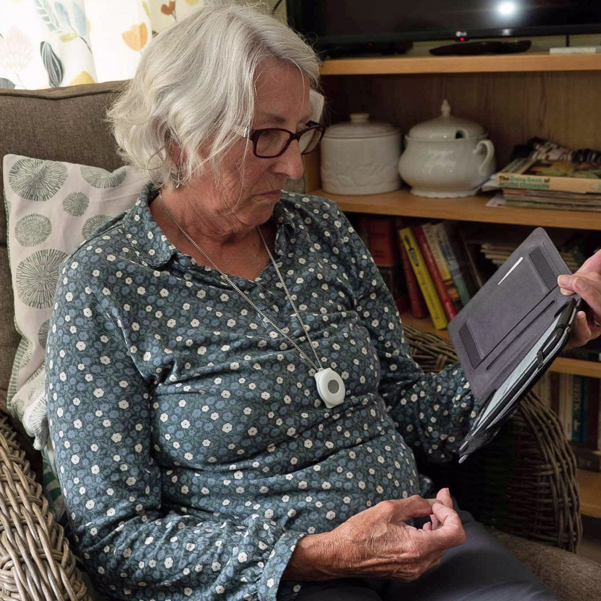older lady sitting wearing a personal alarm