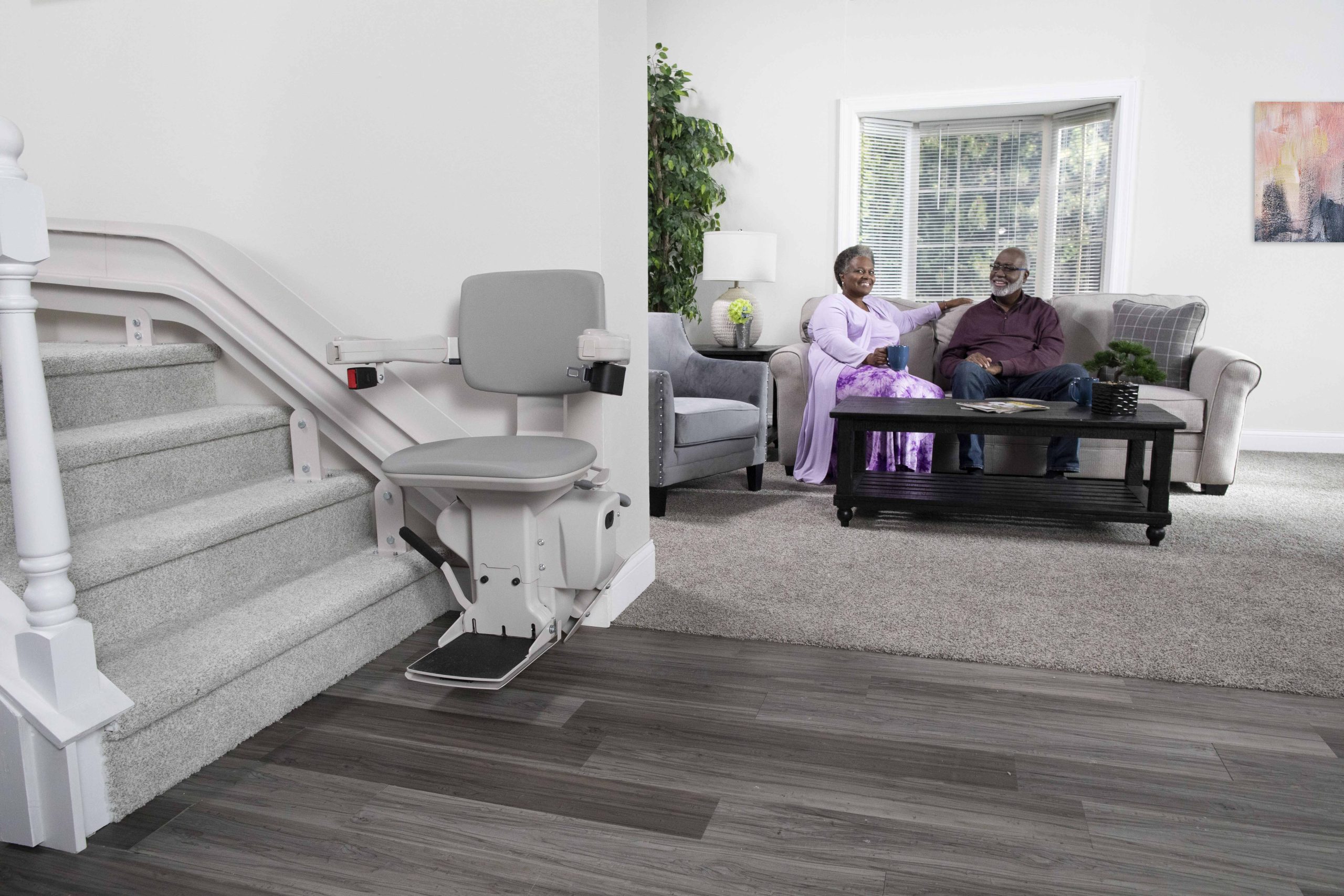 A bruno elite curved stairlift with a family in the background.